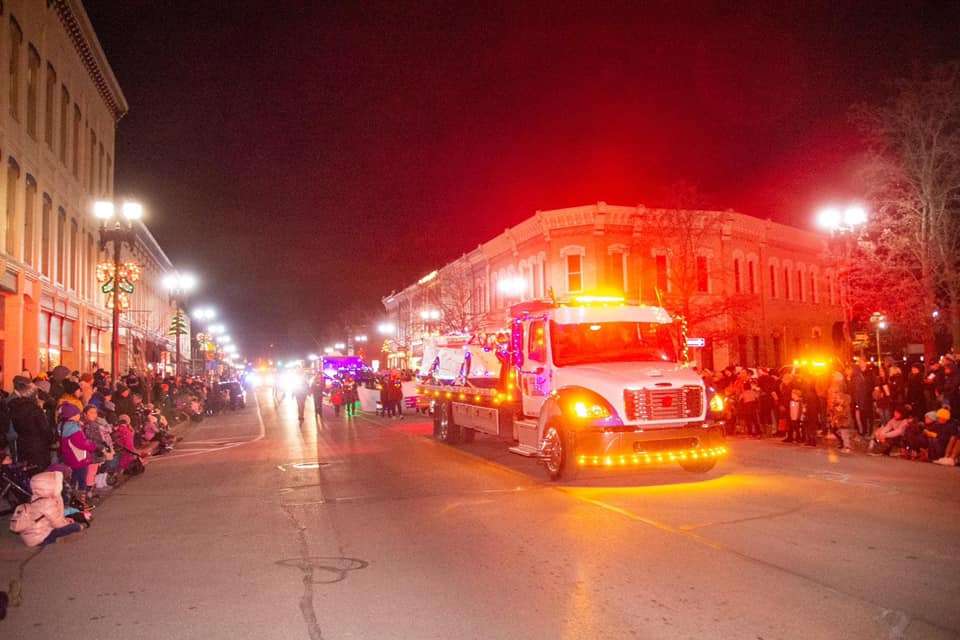 A lit up flat bed tow truck participating in the Lowell Parade.
